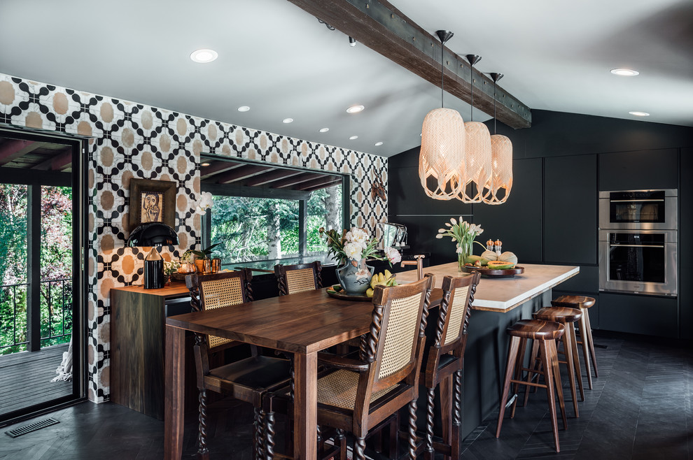 Eclectic l-shaped kitchen/diner in Salt Lake City with flat-panel cabinets, black cabinets, wood worktops, multi-coloured splashback, cement tile splashback, stainless steel appliances, an island and black floors.