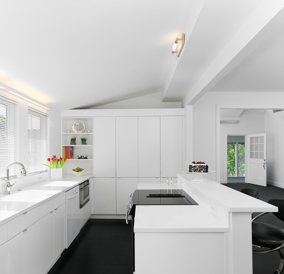 Design ideas for a modern l-shaped open plan kitchen in DC Metro with flat-panel cabinets, white splashback, black appliances and black floors.