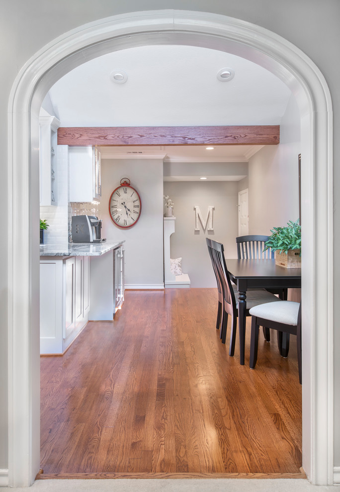Small transitional u-shaped medium tone wood floor and brown floor eat-in kitchen photo in Other with an undermount sink, shaker cabinets, white cabinets, granite countertops, white backsplash, subway tile backsplash, stainless steel appliances, a peninsula and white countertops