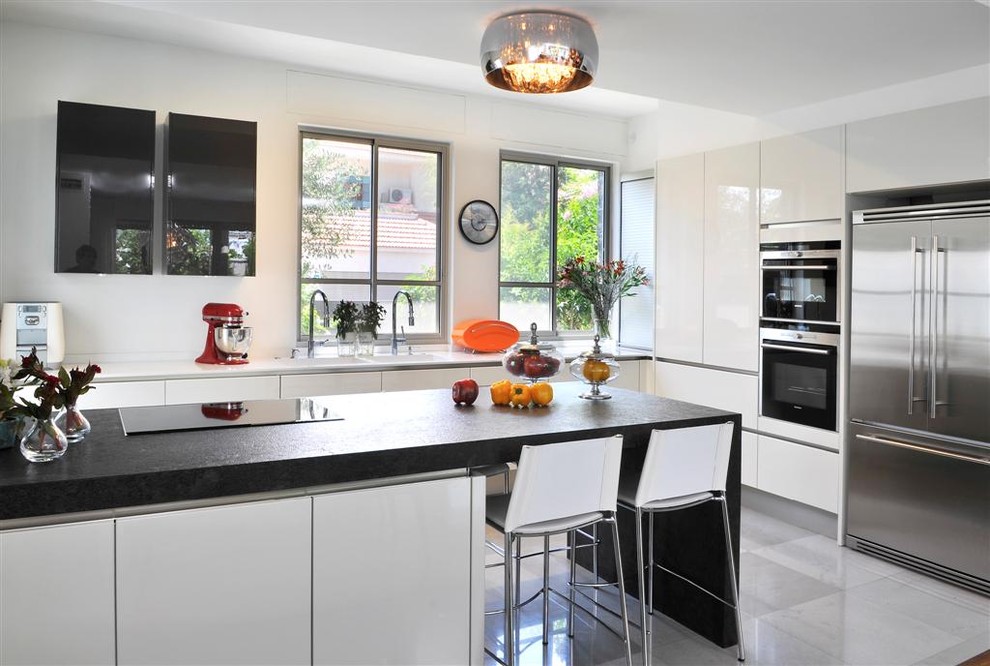 На фото: угловая кухня в стиле модернизм с обеденным столом, двойной мойкой, белыми фасадами и гранитной столешницей с