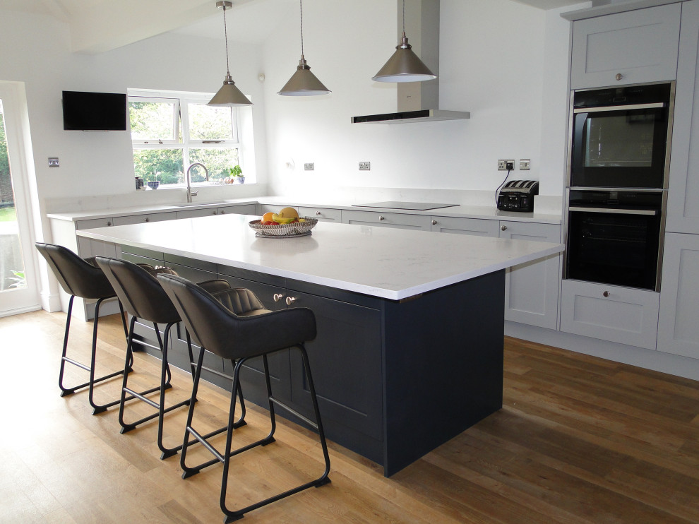 Inspiration for a medium sized contemporary l-shaped kitchen/diner in Other with a double-bowl sink, shaker cabinets, grey cabinets, quartz worktops, stainless steel appliances, an island and white worktops.