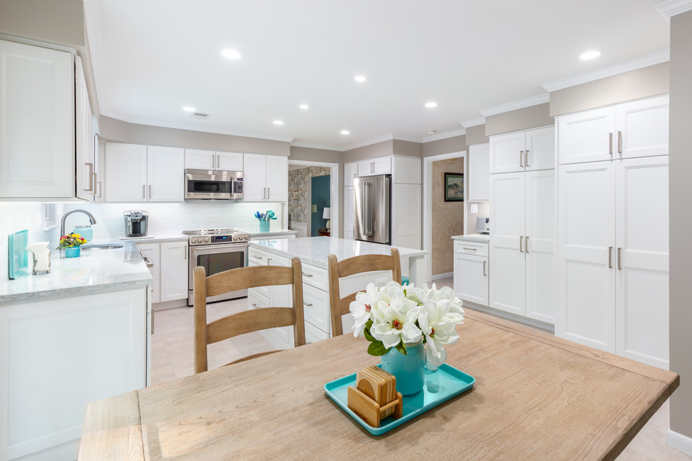 This is an example of a large coastal u-shaped kitchen/diner in DC Metro with a submerged sink, recessed-panel cabinets, white cabinets, quartz worktops, white splashback, ceramic splashback, stainless steel appliances, porcelain flooring, an island, grey floors and white worktops.
