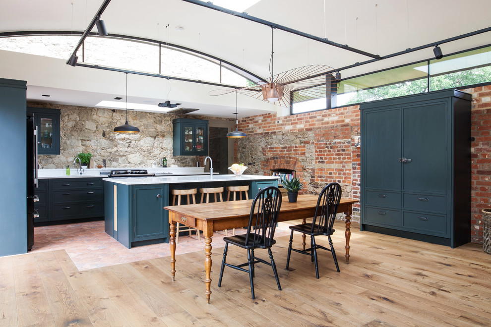 Inspiration for an expansive rural u-shaped kitchen/diner in Kent with granite worktops, black appliances, terracotta flooring, an island, multi-coloured floors, shaker cabinets, blue cabinets, an integrated sink and white worktops.