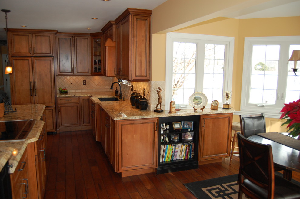 Idéer för ett avskilt, mellanstort klassiskt l-kök, med en undermonterad diskho, luckor med upphöjd panel, bruna skåp, granitbänkskiva, beige stänkskydd, stänkskydd i keramik, integrerade vitvaror, mörkt trägolv, en köksö och brunt golv