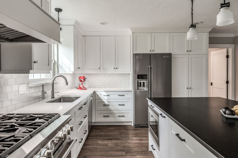 Exempel på ett mellanstort klassiskt vit vitt kök, med en dubbel diskho, skåp i shakerstil, vita skåp, bänkskiva i kvartsit, vitt stänkskydd, stänkskydd i glaskakel, rostfria vitvaror, klinkergolv i porslin, en köksö och brunt golv