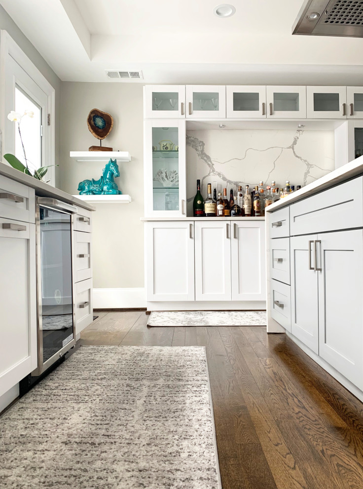 Mid-sized trendy u-shaped dark wood floor and brown floor open concept kitchen photo in DC Metro with a farmhouse sink, shaker cabinets, white cabinets, quartzite countertops, white backsplash, stone slab backsplash, stainless steel appliances, an island and white countertops