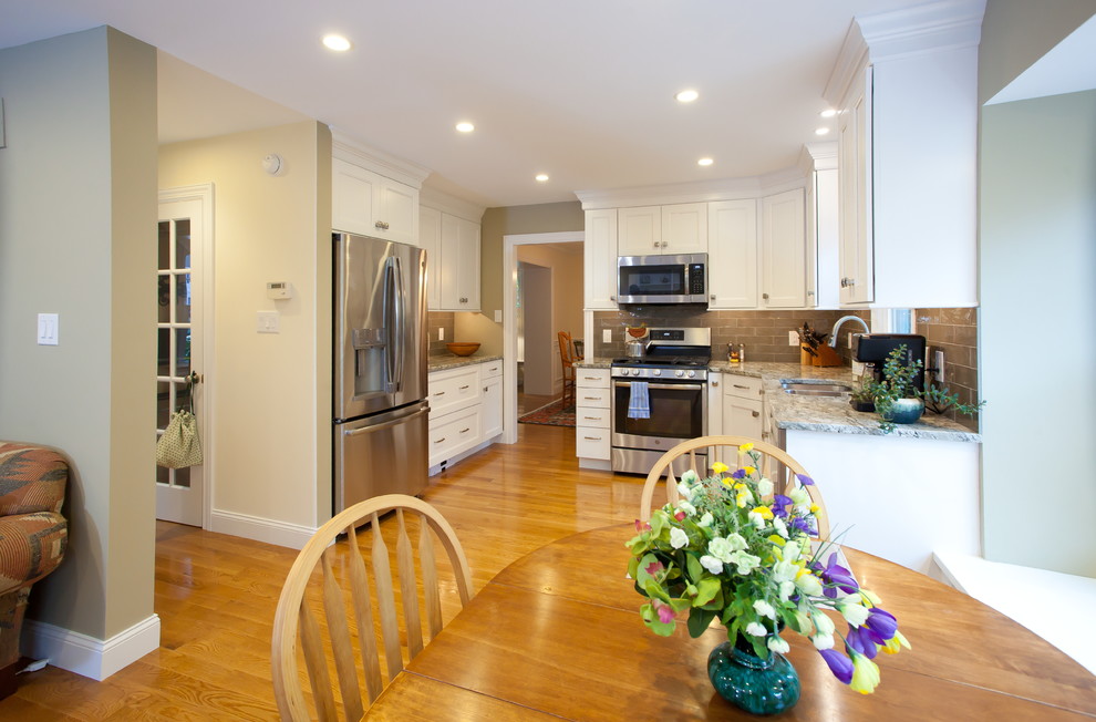 This is an example of a small classic l-shaped open plan kitchen in Philadelphia with a double-bowl sink, shaker cabinets, white cabinets, engineered stone countertops, grey splashback, ceramic splashback, stainless steel appliances, medium hardwood flooring, no island, grey worktops and brown floors.