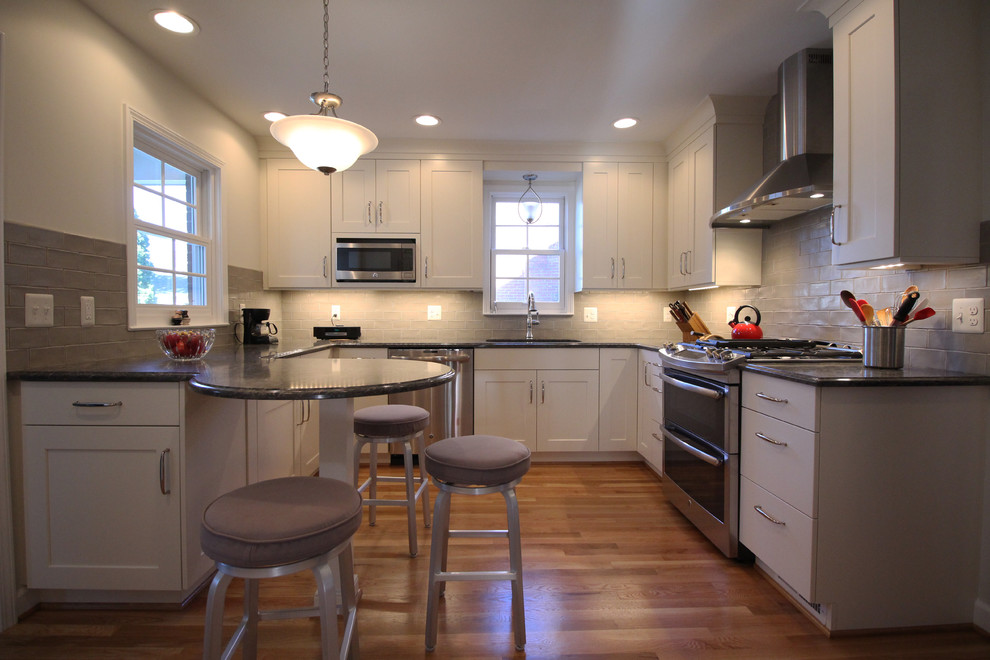 Bild på ett mellanstort vintage kök, med en undermonterad diskho, släta luckor, vita skåp, bänkskiva i kvartsit, grått stänkskydd, stänkskydd i tunnelbanekakel, rostfria vitvaror, ljust trägolv och en halv köksö