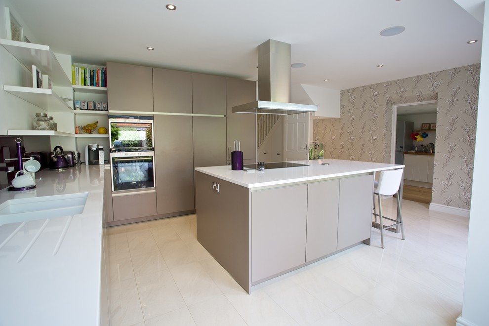 Design ideas for a medium sized contemporary u-shaped kitchen/diner in Hampshire with an integrated sink, flat-panel cabinets, grey cabinets, composite countertops, blue splashback, glass sheet splashback, stainless steel appliances, porcelain flooring and an island.