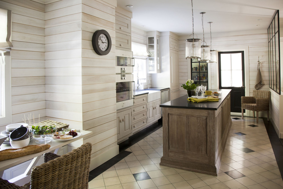 Immagine di una cucina abitabile contemporanea con lavello stile country, ante con bugna sagomata, ante in legno chiaro e elettrodomestici da incasso