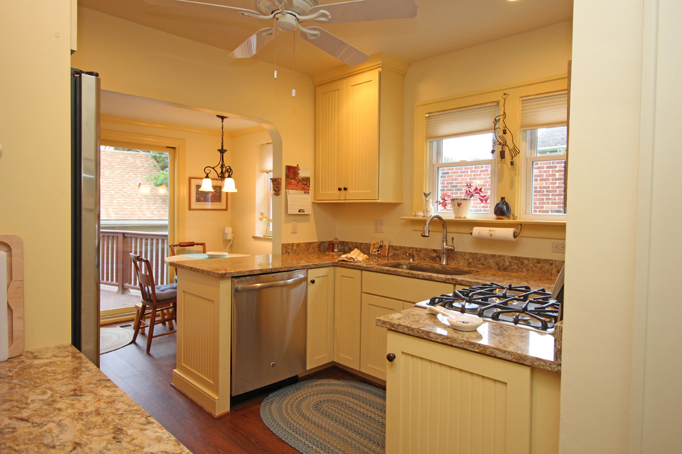 Exempel på ett litet lantligt kök, med en enkel diskho, luckor med infälld panel, gula skåp, bänkskiva i kvarts, flerfärgad stänkskydd, rostfria vitvaror, mellanmörkt trägolv och en halv köksö
