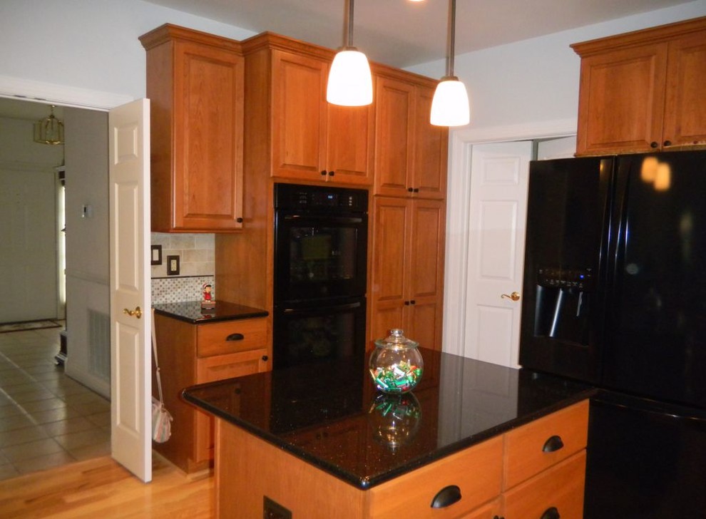 シカゴにあるトラディショナルスタイルのおしゃれなキッチン (レイズドパネル扉のキャビネット、中間色木目調キャビネット、マルチカラーのキッチンパネル、黒い調理設備) の写真