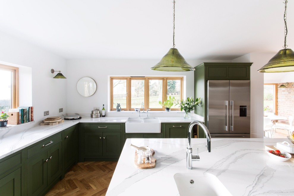 Idéer för att renovera ett stort lantligt vit vitt kök, med en rustik diskho, luckor med profilerade fronter, gröna skåp, bänkskiva i kvartsit, glaspanel som stänkskydd, svarta vitvaror, mellanmörkt trägolv, en köksö och brunt golv