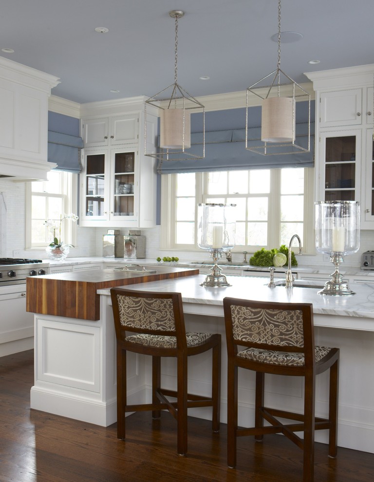 Exempel på ett stort klassiskt kök, med luckor med profilerade fronter, träbänkskiva, vita skåp, en undermonterad diskho, vitt stänkskydd, rostfria vitvaror, korkgolv, en köksö och brunt golv