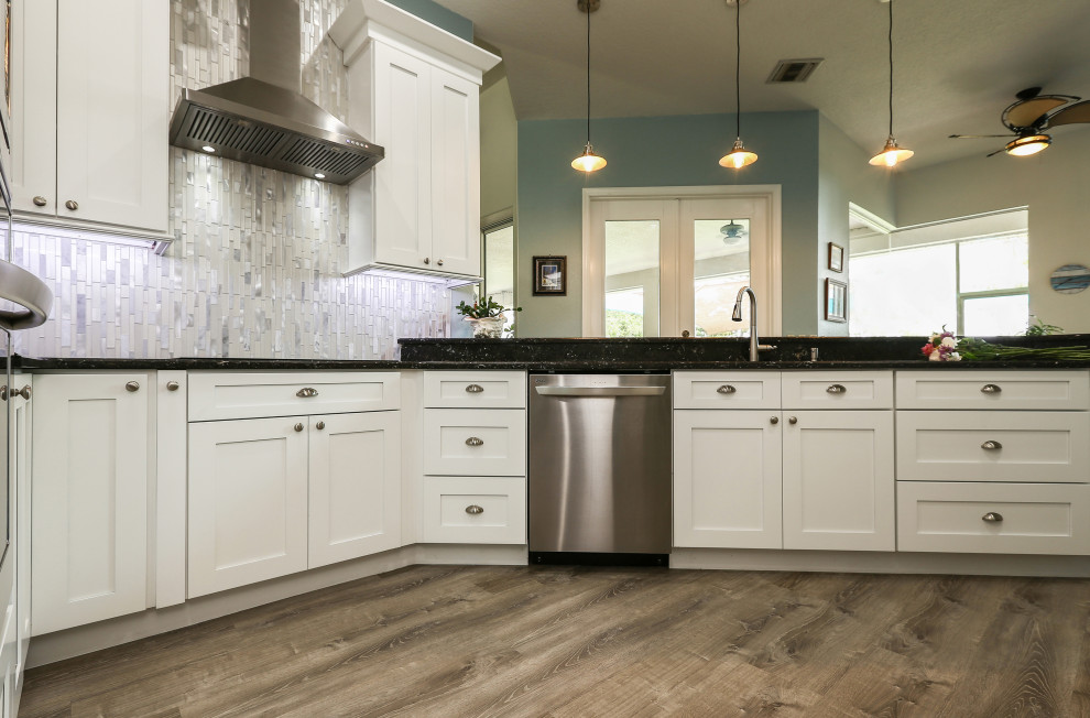 Modern inredning av ett avskilt, mellanstort svart svart u-kök, med en dubbel diskho, skåp i shakerstil, vita skåp, granitbänkskiva, stänkskydd med metallisk yta, glaspanel som stänkskydd, rostfria vitvaror, vinylgolv, en köksö och grått golv