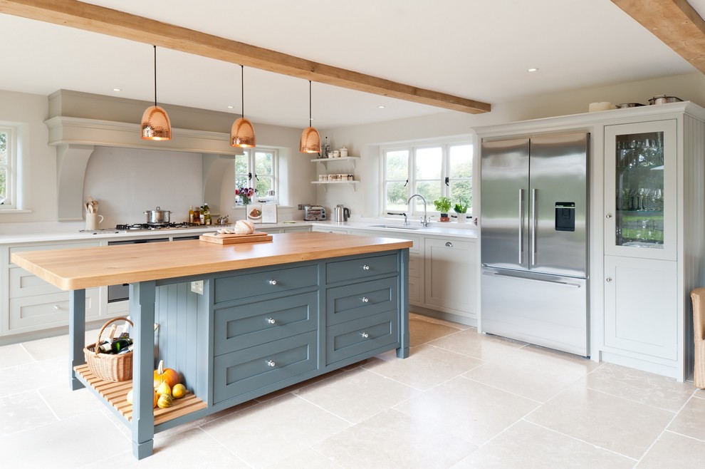 Design ideas for a large farmhouse l-shaped kitchen/diner in Kent with flat-panel cabinets, blue cabinets, composite countertops, white splashback, stone tiled splashback, stainless steel appliances, limestone flooring and an island.