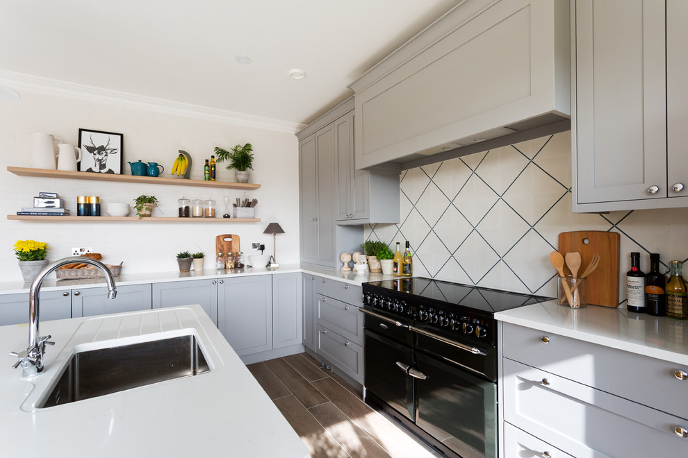 Design ideas for a medium sized traditional l-shaped kitchen/diner in Dublin with a single-bowl sink, shaker cabinets, grey cabinets, quartz worktops, white splashback, cement tile splashback, black appliances, porcelain flooring, an island, brown floors and white worktops.