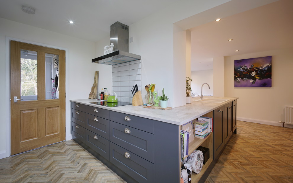 Inspiration for a large contemporary l-shaped open plan kitchen in Belfast with a double-bowl sink, shaker cabinets, grey cabinets, laminate countertops, white splashback, ceramic splashback, integrated appliances, vinyl flooring, a breakfast bar, brown floors and grey worktops.