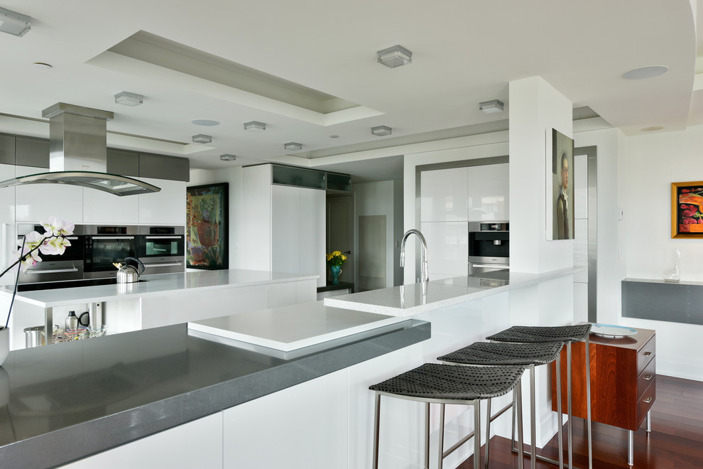 Foto på ett stort funkis kök och matrum, med släta luckor, vita skåp, bänkskiva i koppar, rostfria vitvaror, mellanmörkt trägolv, en köksö och brunt golv