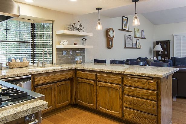 Inredning av ett klassiskt mellanstort kök, med en undermonterad diskho, luckor med infälld panel, skåp i mellenmörkt trä, granitbänkskiva, vitt stänkskydd, stänkskydd i glaskakel, rostfria vitvaror, mellanmörkt trägolv och en halv köksö