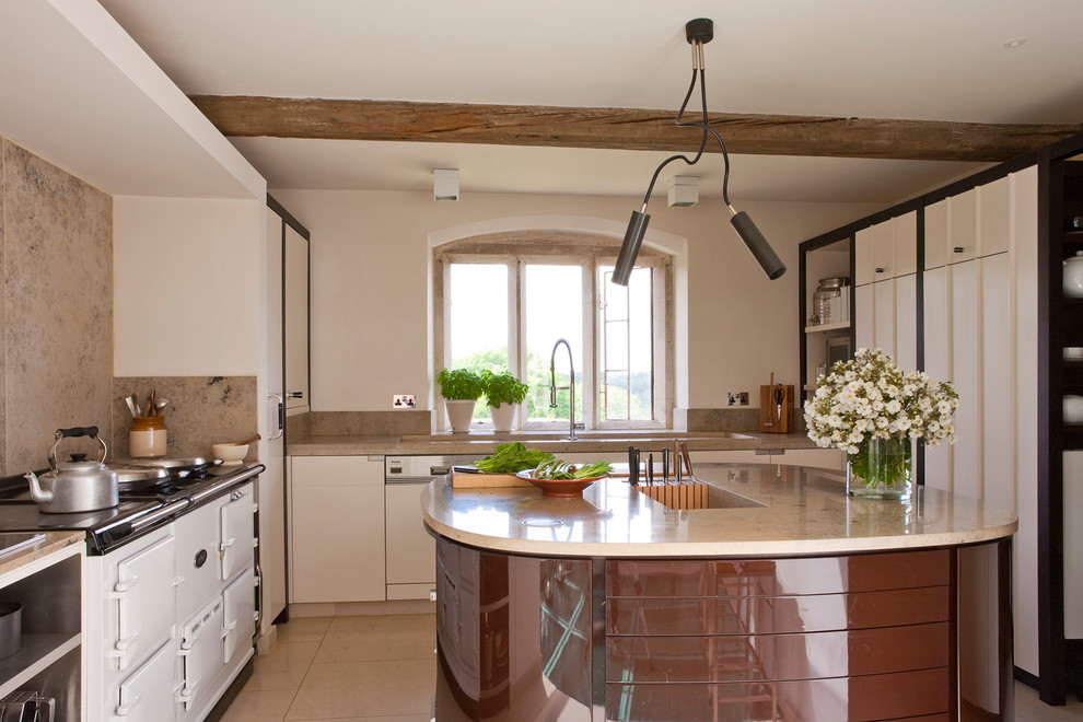 Inspiration for a medium sized country u-shaped enclosed kitchen in Gloucestershire with flat-panel cabinets, white cabinets, stone tiled splashback, white appliances, an island, a submerged sink, beige splashback, beige floors and beige worktops.