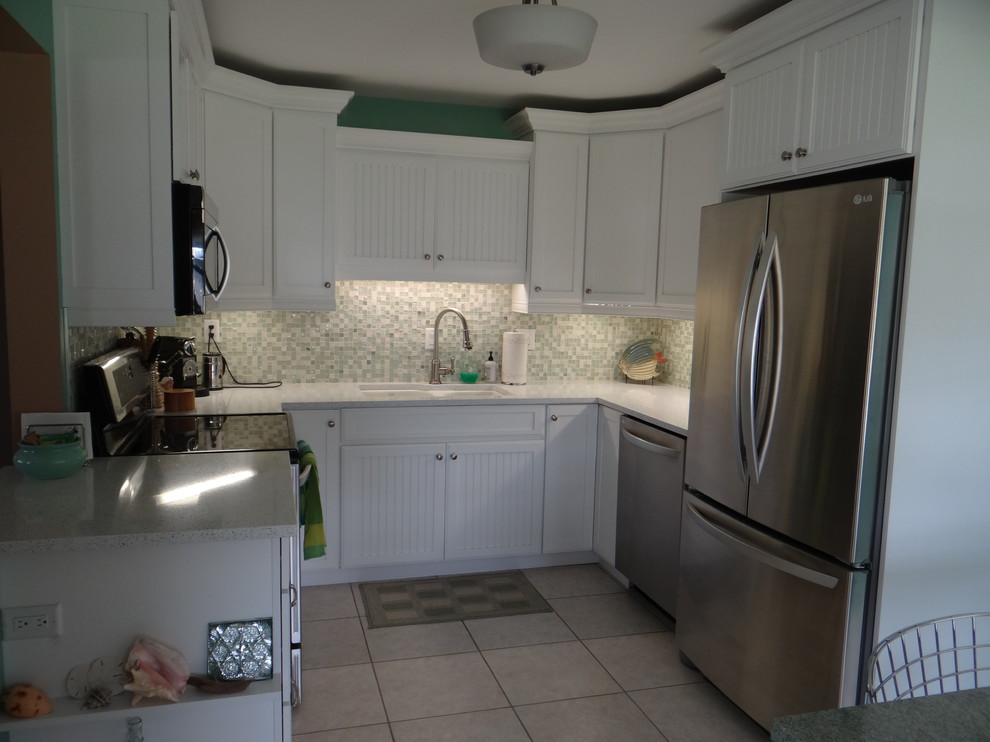 Example of a small beach style u-shaped ceramic tile open concept kitchen design in Tampa with an undermount sink, shaker cabinets, white cabinets, quartz countertops, green backsplash, glass tile backsplash, stainless steel appliances and an island