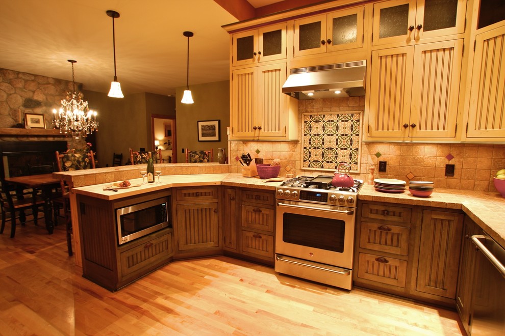 Bild på ett mellanstort rustikt kök, med en rustik diskho, vita skåp, beige stänkskydd, rostfria vitvaror, en halv köksö, luckor med lamellpanel, stänkskydd i keramik och bambugolv