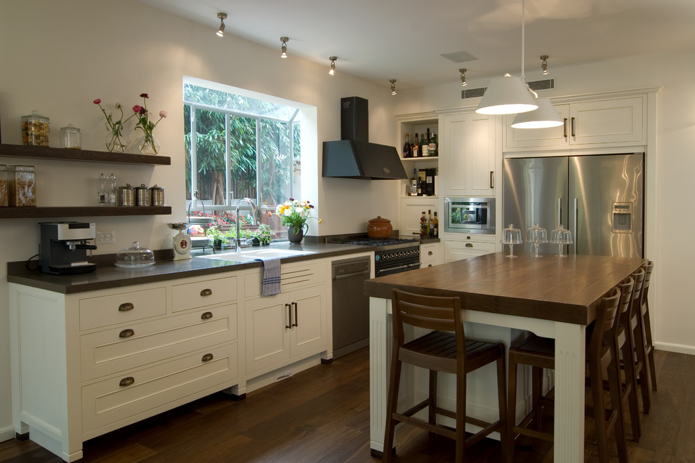 Cette photo montre une cuisine tendance en L avec un électroménager en acier inoxydable, un évier posé et des portes de placard blanches.