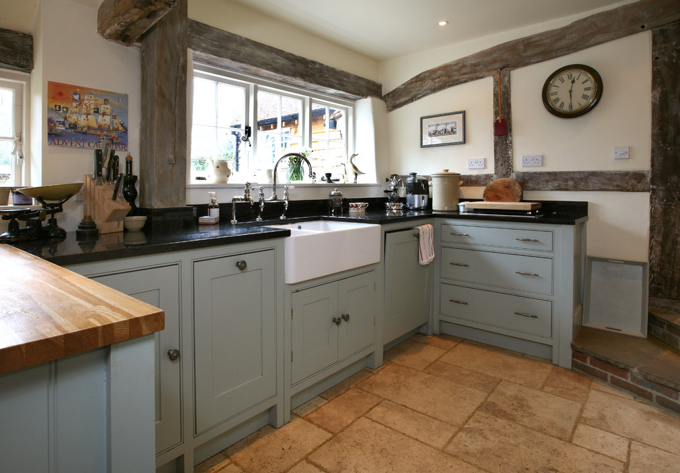 Foto de cocina de estilo de casa de campo grande con armarios estilo shaker, puertas de armario azules, encimera de granito, salpicadero blanco, suelo beige y encimeras negras