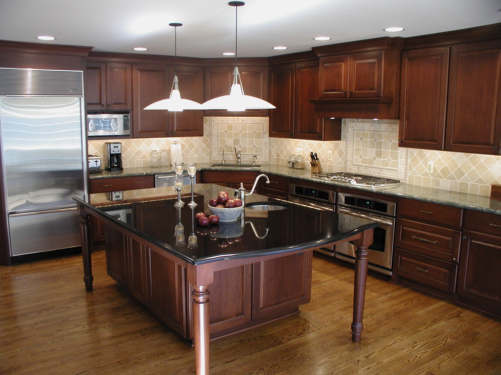 Eat-in kitchen - traditional l-shaped eat-in kitchen idea in Detroit with an undermount sink, raised-panel cabinets, dark wood cabinets, granite countertops, beige backsplash, stone tile backsplash and stainless steel appliances