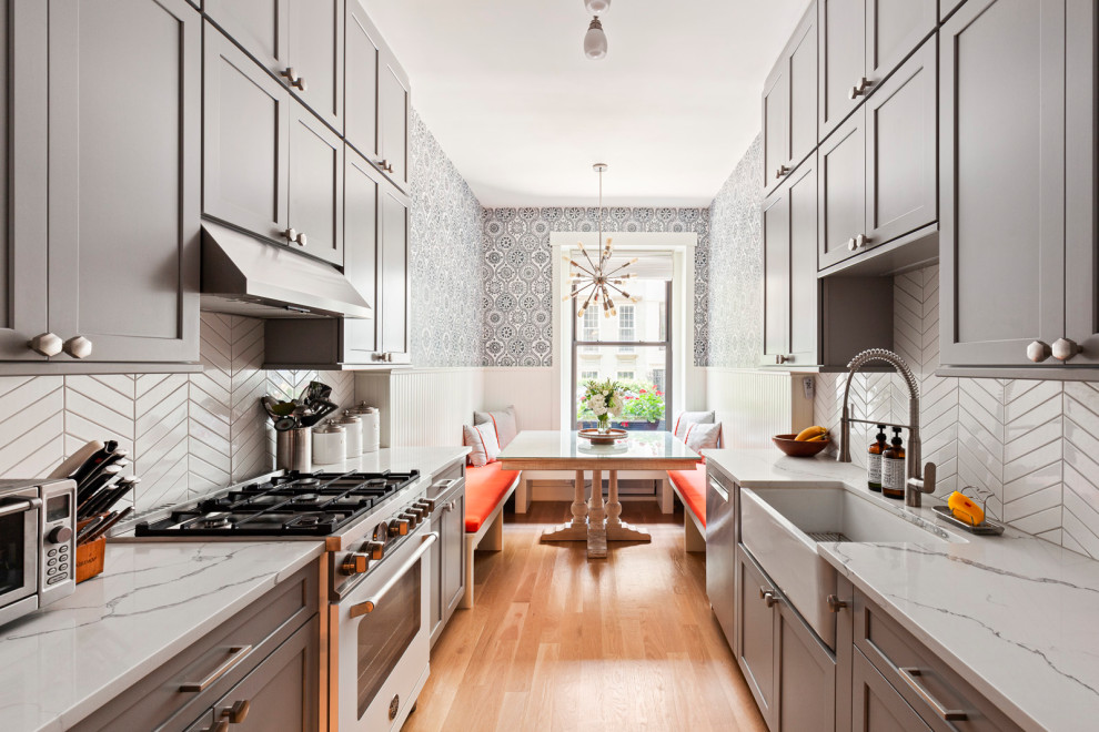 Inspiration for a transitional galley medium tone wood floor and brown floor eat-in kitchen remodel in New York with a farmhouse sink, shaker cabinets, gray cabinets, white backsplash, stainless steel appliances, no island and white countertops
