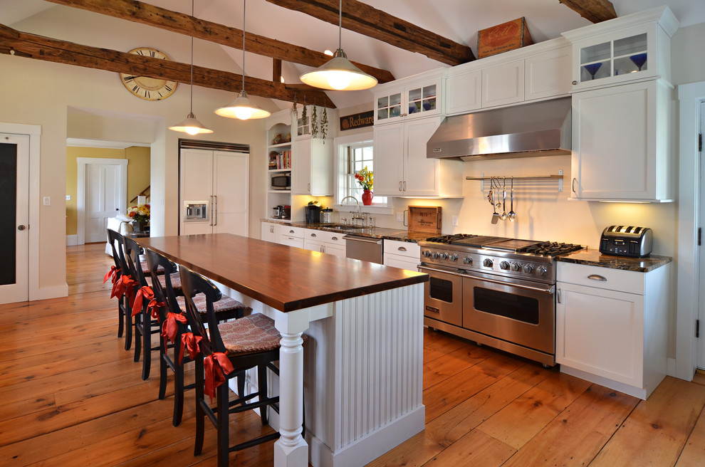 Country Küche in L-Form mit Schrankfronten im Shaker-Stil, weißen Schränken, braunem Holzboden, Kücheninsel, Unterbauwaschbecken, Granit-Arbeitsplatte, Küchenrückwand in Weiß und Küchengeräten aus Edelstahl in Boston