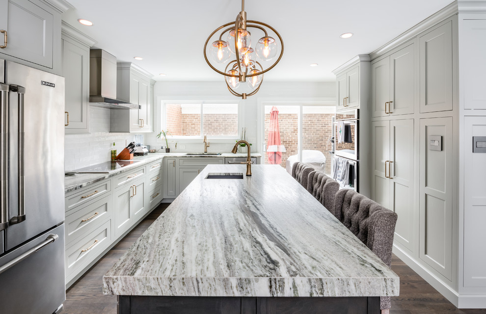 Photo of a medium sized contemporary u-shaped kitchen/diner in DC Metro with a submerged sink, shaker cabinets, white cabinets, white splashback, metro tiled splashback, stainless steel appliances, dark hardwood flooring, an island, brown floors and multicoloured worktops.