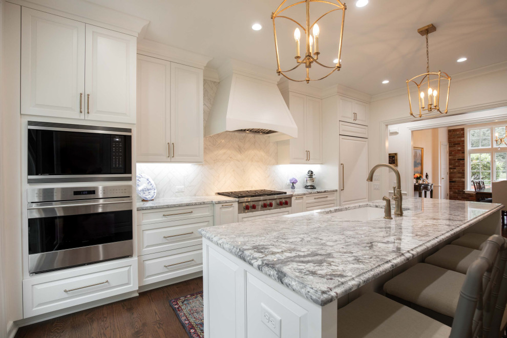 Kitchen - mid-sized traditional u-shaped medium tone wood floor and brown floor kitchen idea in Indianapolis with an undermount sink, raised-panel cabinets, white cabinets, quartz countertops, white backsplash, ceramic backsplash, paneled appliances, an island and white countertops