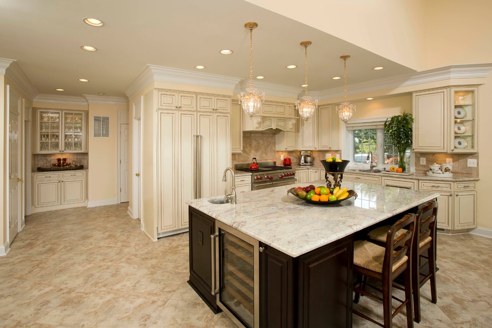 Inspiration for a mid-sized timeless l-shaped travertine floor and beige floor open concept kitchen remodel in DC Metro with a double-bowl sink, raised-panel cabinets, beige cabinets, granite countertops, beige backsplash, stone slab backsplash, stainless steel appliances and an island