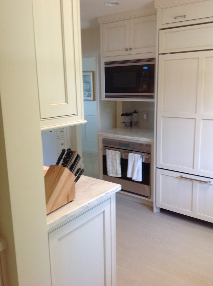 Inspiration for a mid-sized timeless u-shaped travertine floor enclosed kitchen remodel in Miami with an undermount sink, shaker cabinets, white cabinets, quartzite countertops, gray backsplash, stone slab backsplash, stainless steel appliances and a peninsula