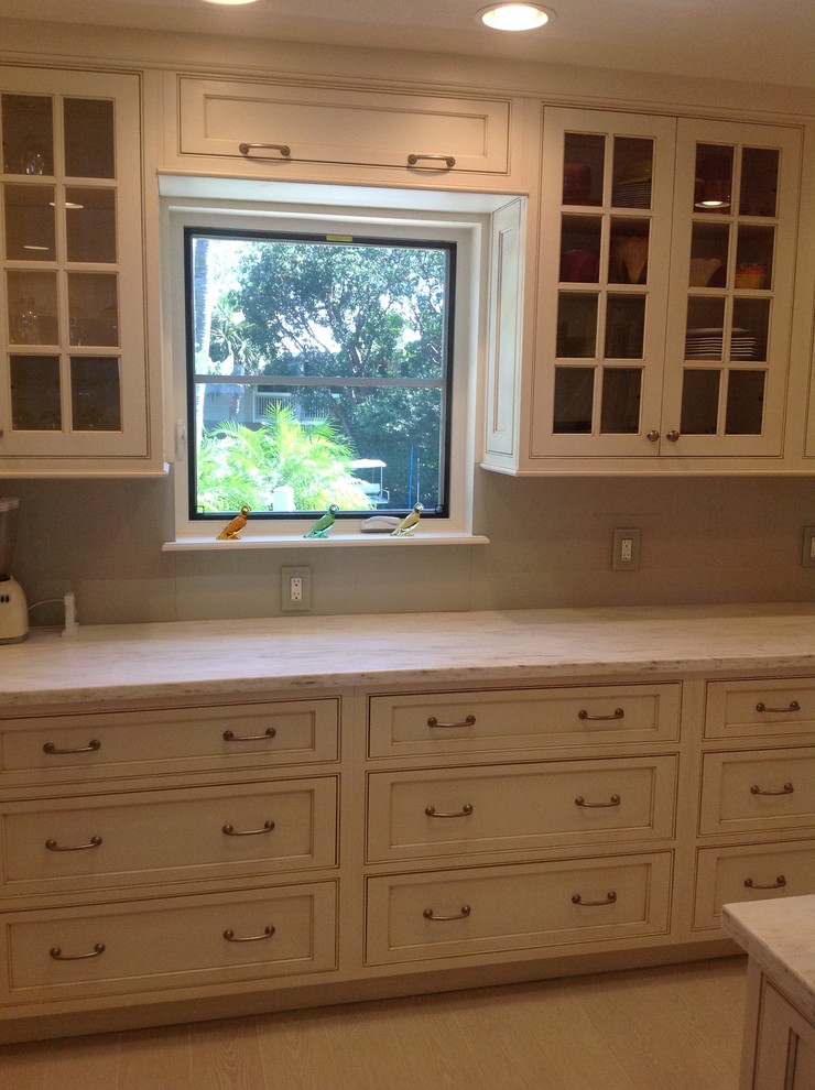 Mid-sized elegant u-shaped travertine floor enclosed kitchen photo in Miami with an undermount sink, shaker cabinets, white cabinets, quartzite countertops, gray backsplash, stone slab backsplash, stainless steel appliances and a peninsula