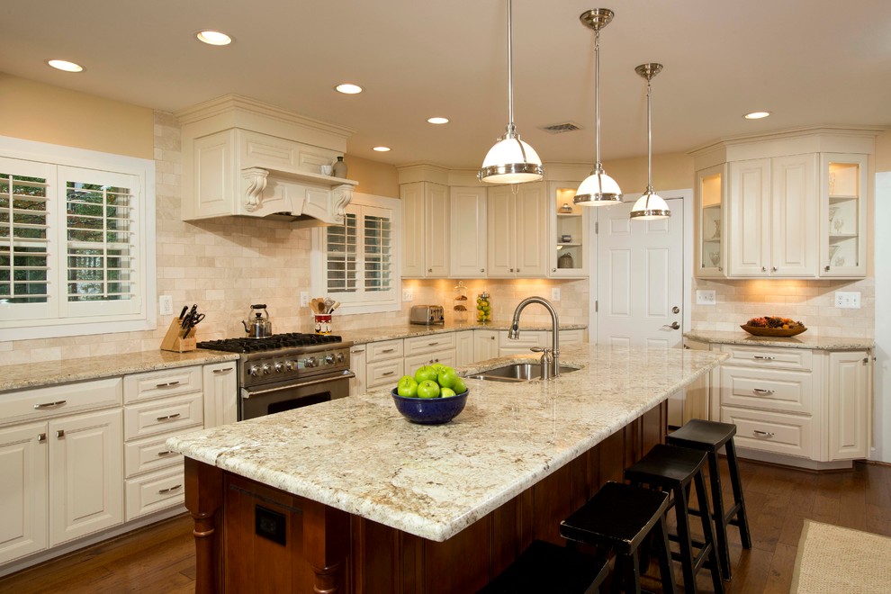 Exempel på ett mellanstort klassiskt kök, med en dubbel diskho, luckor med upphöjd panel, vita skåp, granitbänkskiva, beige stänkskydd, stänkskydd i keramik, rostfria vitvaror, mörkt trägolv, en köksö och brunt golv