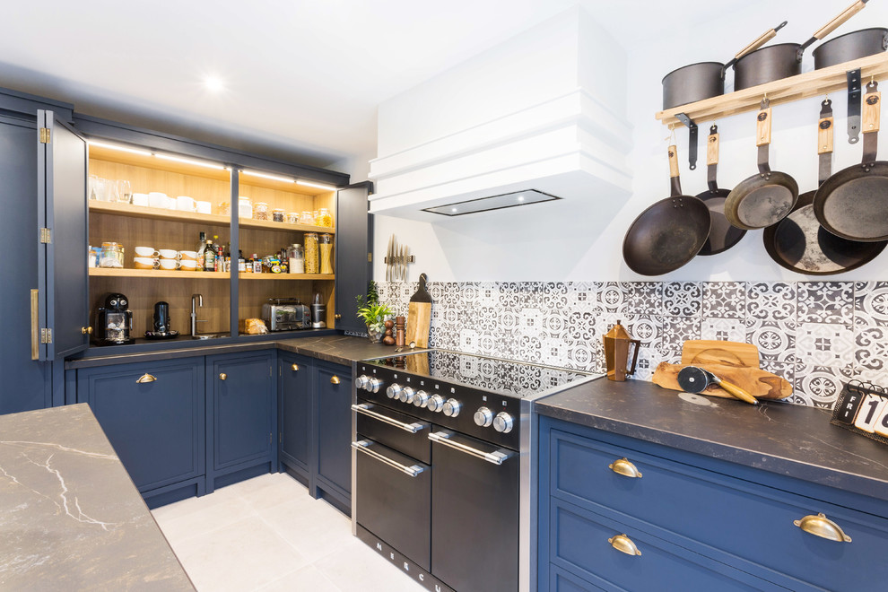 Large urban l-shaped porcelain tile and gray floor eat-in kitchen photo in Essex with a double-bowl sink, shaker cabinets, blue cabinets, solid surface countertops, multicolored backsplash, ceramic backsplash, black appliances, an island and black countertops