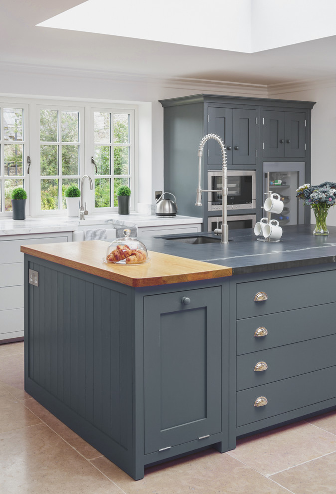 Modern inredning av ett stort kök, med en undermonterad diskho, skåp i shakerstil, grå skåp, marmorbänkskiva, rostfria vitvaror och en köksö
