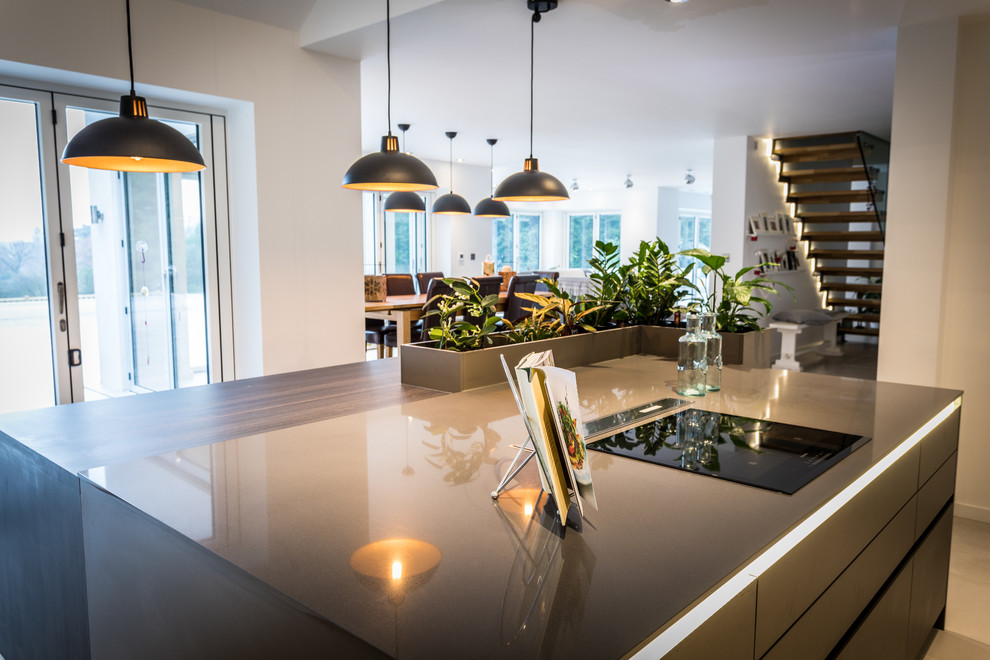 Medium sized contemporary u-shaped open plan kitchen in Hampshire with a submerged sink, flat-panel cabinets, distressed cabinets, composite countertops, grey splashback, stainless steel appliances and an island.