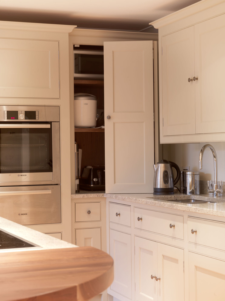 Immagine di una cucina classica di medie dimensioni con lavello da incasso, ante in stile shaker, ante beige, top in granito, elettrodomestici in acciaio inossidabile e parquet chiaro