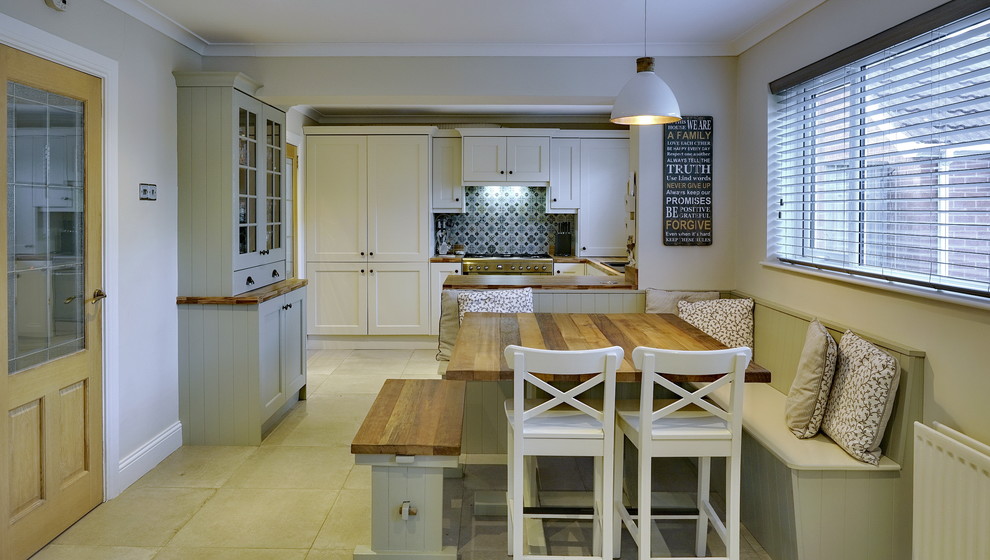Medium sized country u-shaped open plan kitchen in Other with an integrated sink, shaker cabinets, beige cabinets, laminate countertops, green splashback, ceramic splashback, stainless steel appliances, ceramic flooring, a breakfast bar, beige floors and brown worktops.