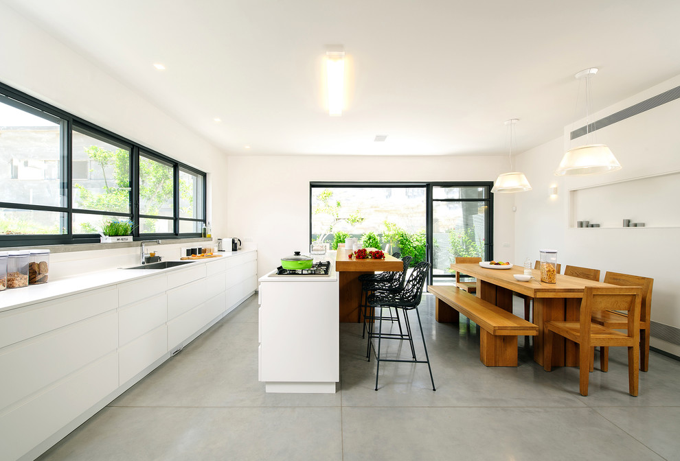 На фото: кухня в современном стиле с плоскими фасадами, белыми фасадами, врезной мойкой и обеденным столом с