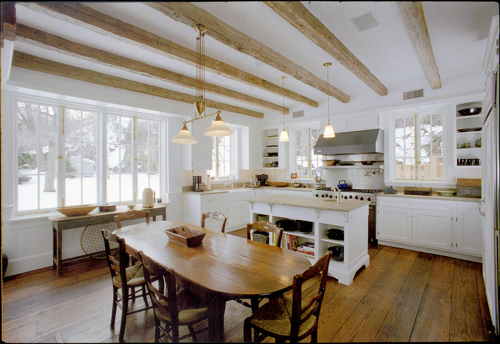 Open concept kitchen - mid-sized cottage u-shaped dark wood floor open concept kitchen idea in New York with a farmhouse sink, recessed-panel cabinets, white cabinets, limestone countertops, beige backsplash, stone slab backsplash, stainless steel appliances and an island