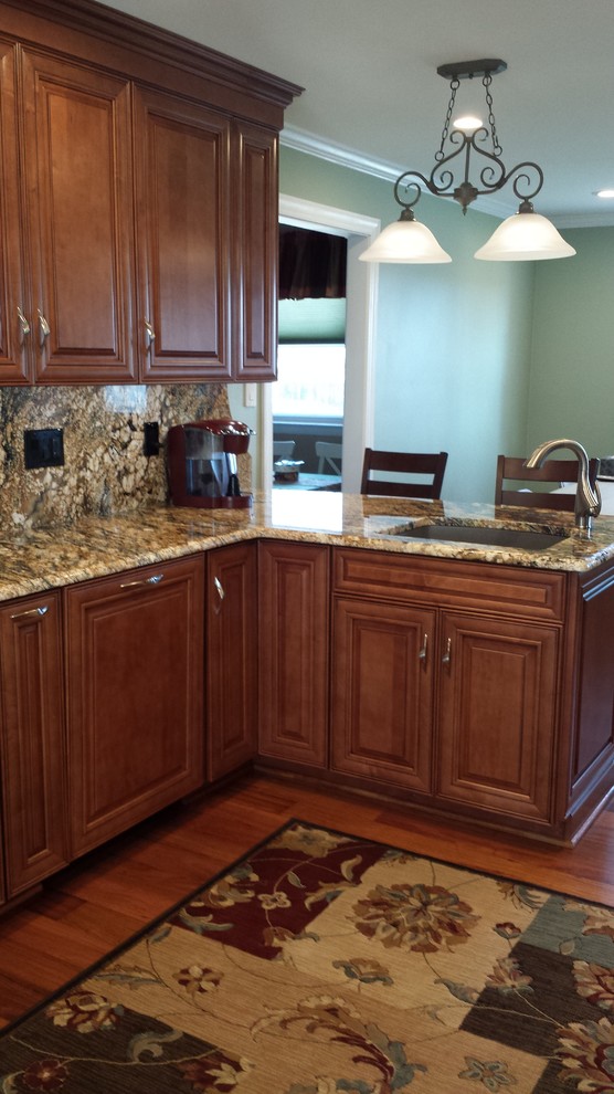 Exempel på ett mellanstort klassiskt kök, med en undermonterad diskho, luckor med upphöjd panel, skåp i mellenmörkt trä, granitbänkskiva, flerfärgad stänkskydd, stänkskydd i sten, rostfria vitvaror, mellanmörkt trägolv och en halv köksö