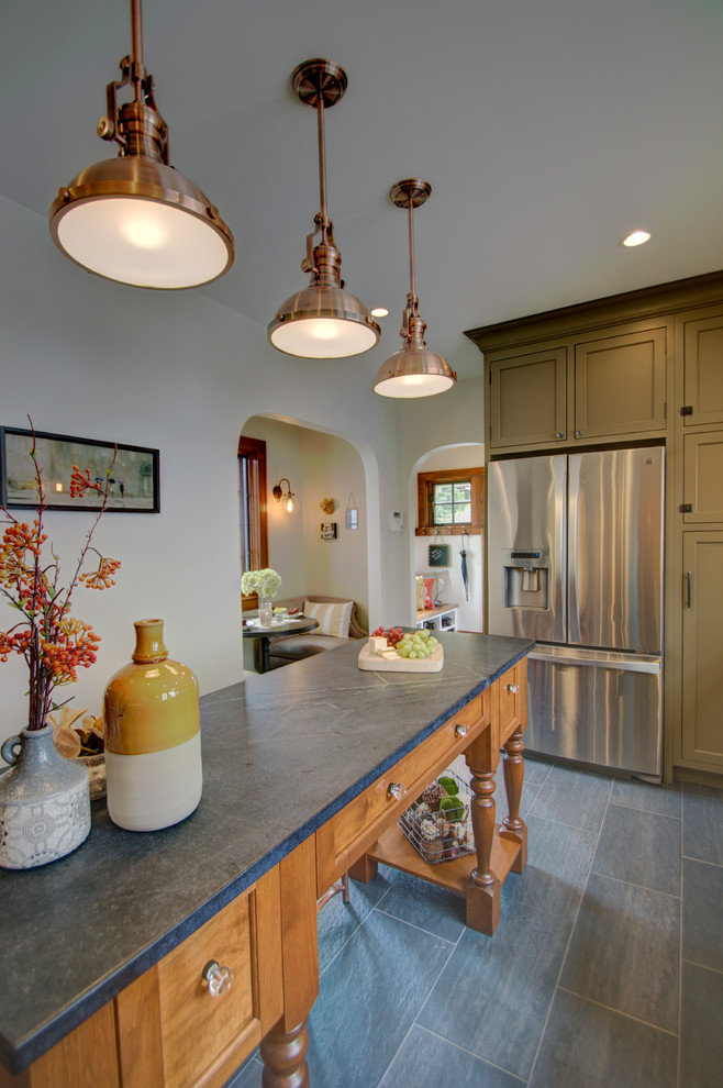 Eat-in kitchen - small eclectic u-shaped porcelain tile eat-in kitchen idea in Columbus with an undermount sink, beaded inset cabinets, medium tone wood cabinets, soapstone countertops, beige backsplash, subway tile backsplash, stainless steel appliances and an island