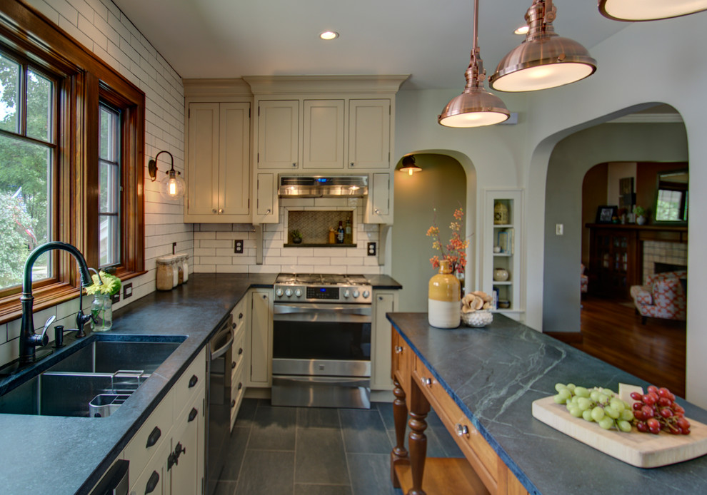 Example of a small eclectic u-shaped porcelain tile eat-in kitchen design in Columbus with an undermount sink, beaded inset cabinets, beige cabinets, soapstone countertops, beige backsplash, subway tile backsplash, stainless steel appliances and an island