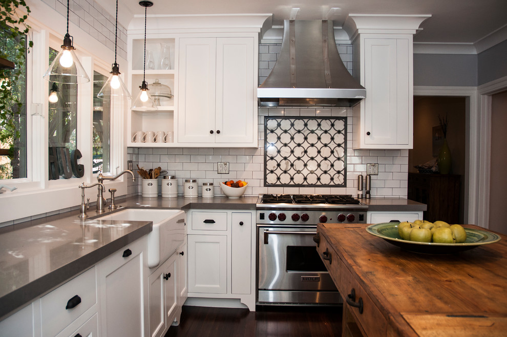 Inspiration for a mid-sized eclectic u-shaped dark wood floor and brown floor enclosed kitchen remodel in Los Angeles with a farmhouse sink, shaker cabinets, white cabinets, quartz countertops, white backsplash, subway tile backsplash, stainless steel appliances, an island and gray countertops