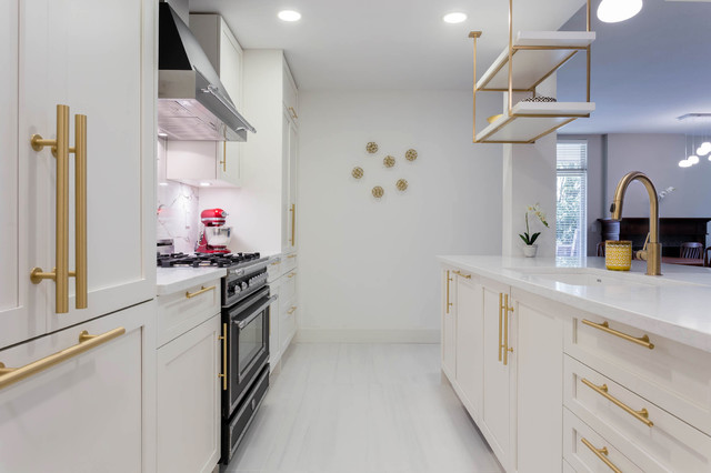 A kitchen with white shaker cabinets and Gold / Brass hardware